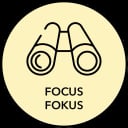 Eine einfache Strichzeichnung eines Fernglases in einem gelben Kreis, darunter die Wörter FOCUS und FOKUS in schwarzen Großbuchstaben.