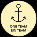 Ein einfaches schwarzes Ankersymbol in einem gelben Kreis mit schwarzem Rand. Unter dem Anker steht in fetten schwarzen Großbuchstaben „ONE TEAM EIN TEAM“.